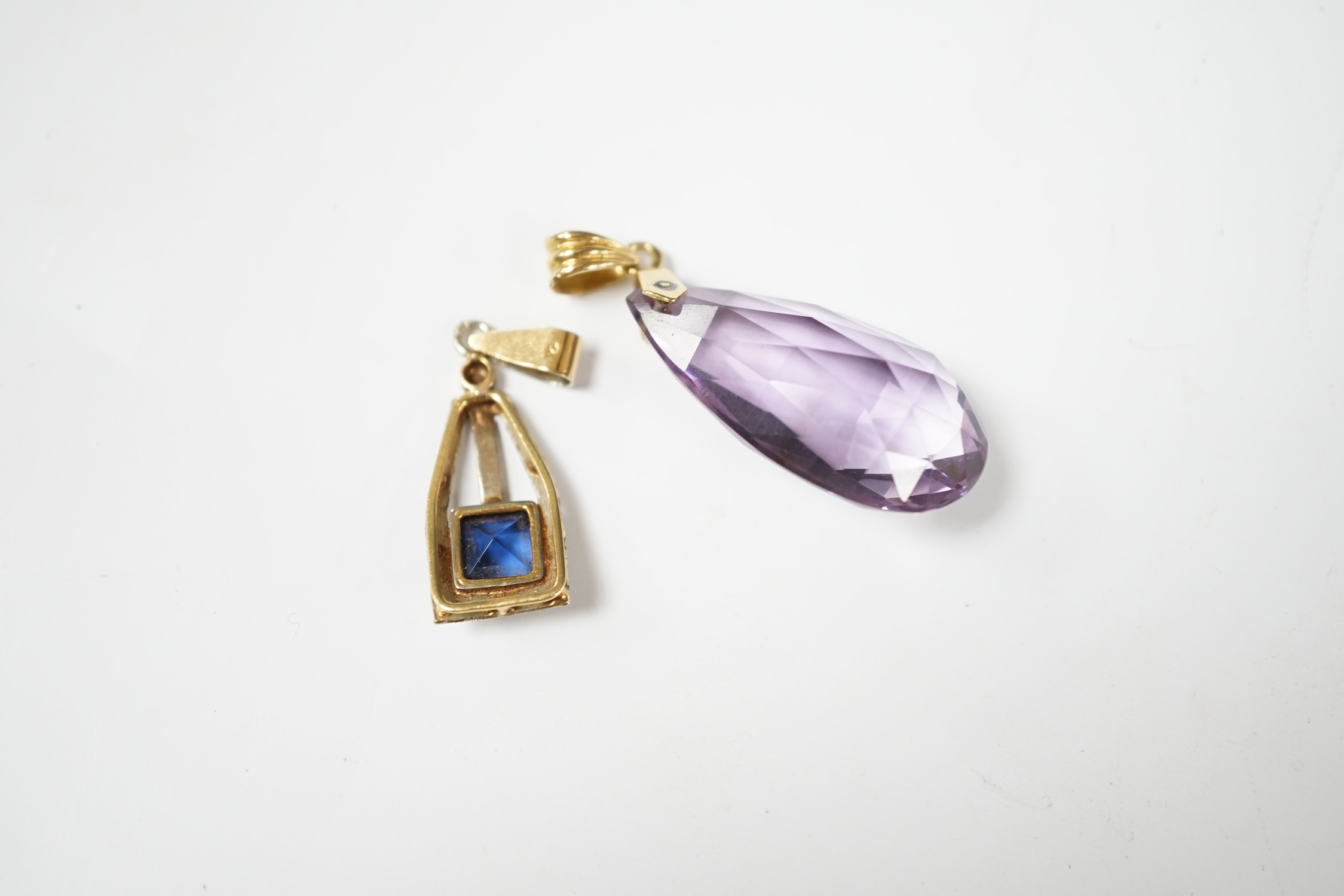 A yellow metal and fancy cut amethyst set drop pendant, 38mm, together with one other blue paste set pendant. Condition - fair